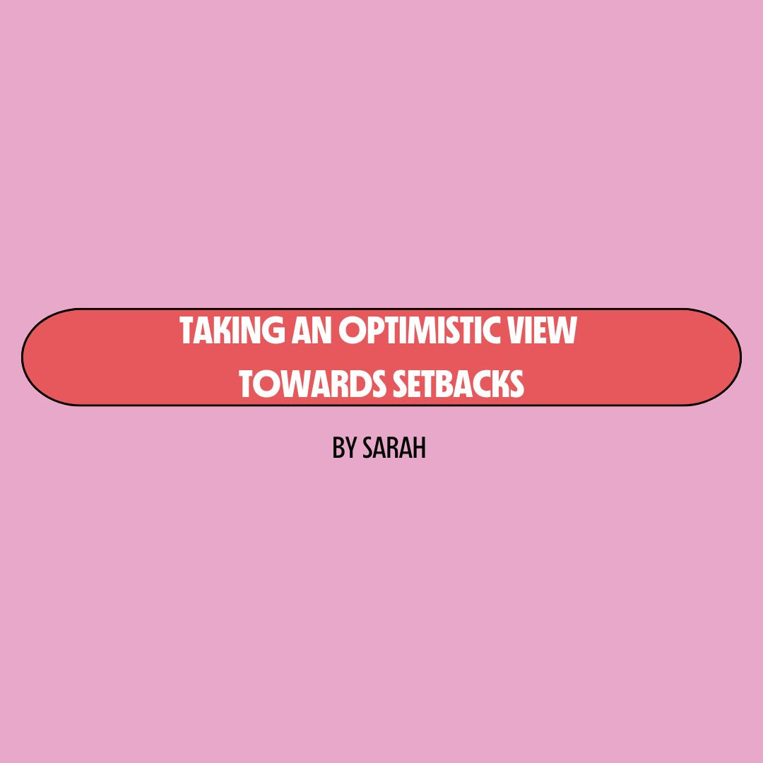 Pink background with a red text box containing white writing that reads: "taking an optimistic view towards setbacks." Underneath is black writing that reads: "by Sarah."